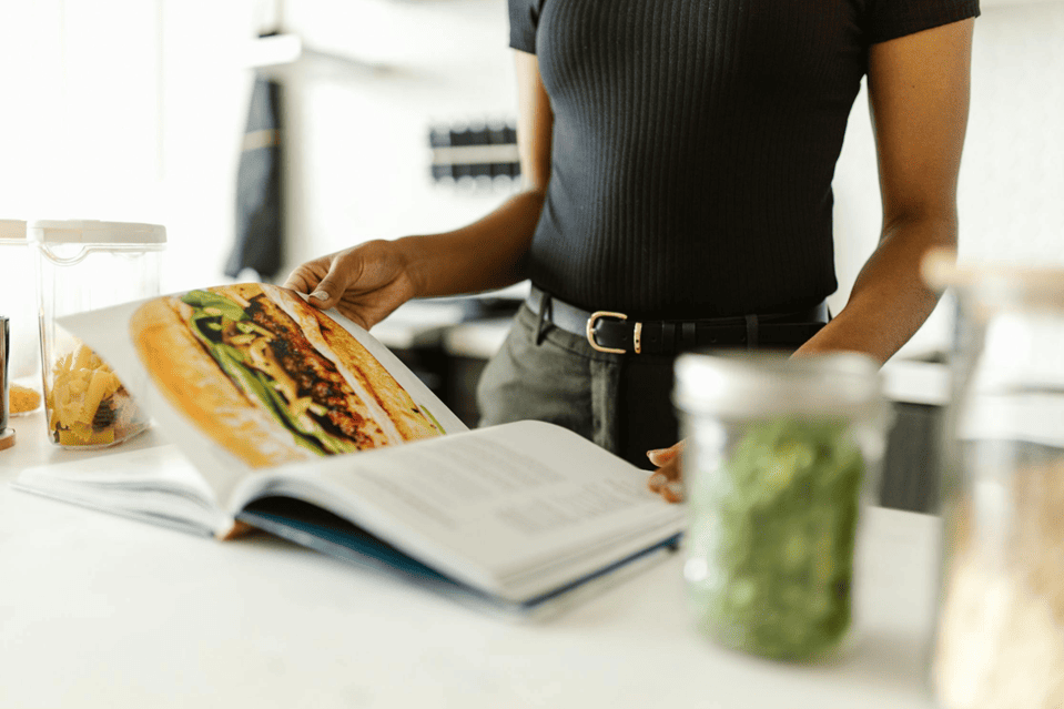 vrouw die in kookboek kijkt om afwisselend maaltijdoverzicht te maken